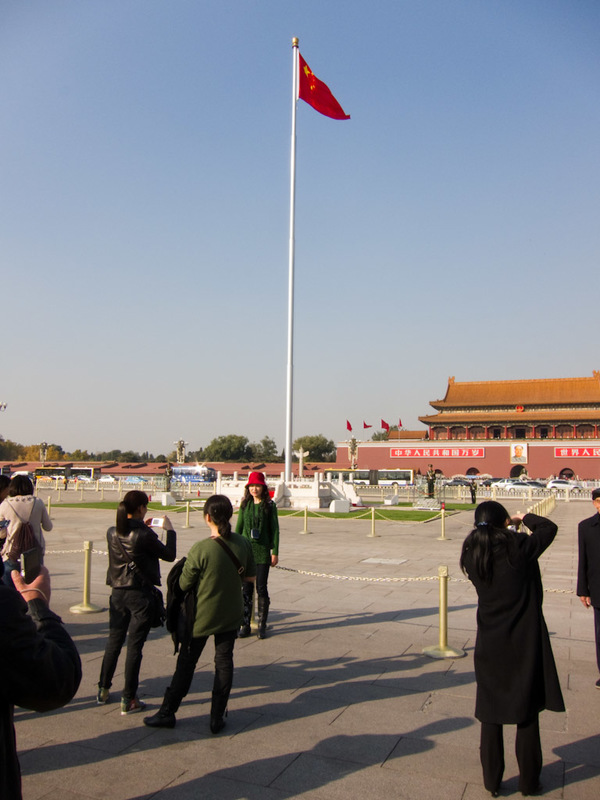 China-Beijing-Tiananmen Square - A large flag, soldiers stand to attention in perspex booths whilst others goose step around it.