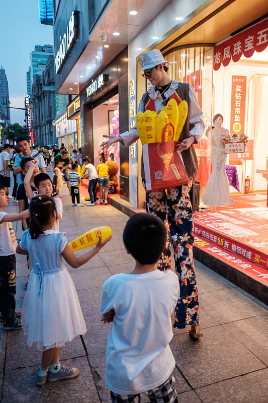 China-Wuhan-Pedestrian Street-Mall - There were lots of people on stilts doing things, this guys is playing rock paper scissors with children.