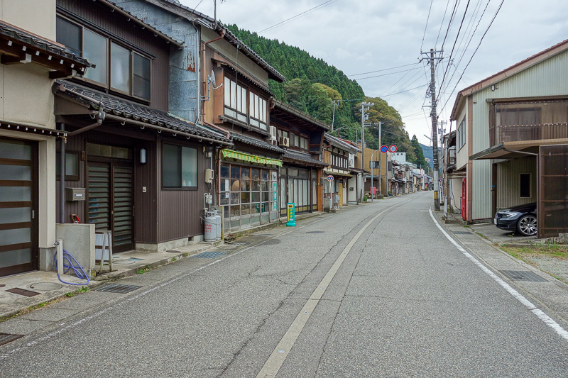 Japan-Kanazawa-Hiking-Tsurugi-Shiritakayama - Nice street, but these used to be shops, now they are houses or abandoned. Except that car poking out is a BMW M6. Probably the head of the shrine vis