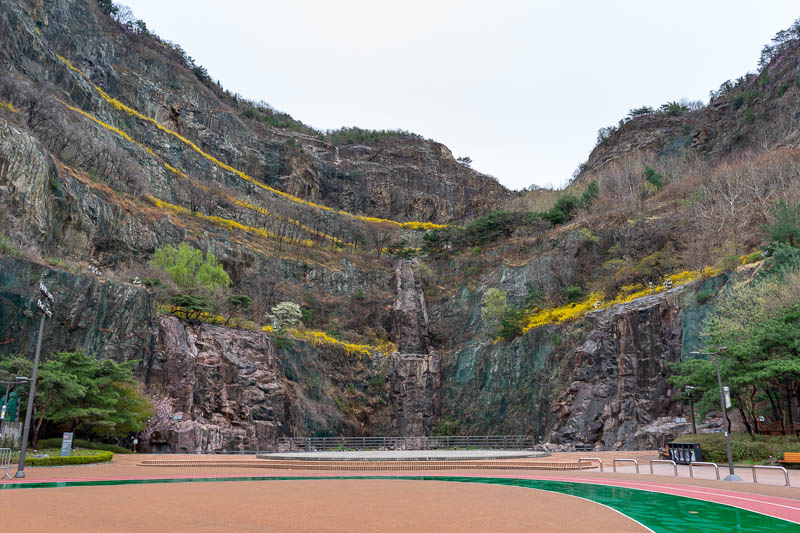 Korea-Seoul-Hiking-Yongmasan - Here is a bit more of the quarry, someone has planted millions of whatever hedge thing produce those yellow flowers. I ran a few laps in the rain.